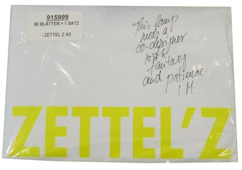 Verpackter Zettelsatz A5 für Ingo Maurer Zettel'z Leuchte mit gelbem Schriftzug und handschriftlichem Zitat.